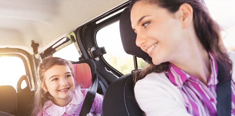 Mom smiling at child in the back seat of car