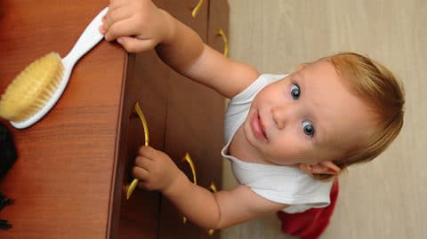 Child climbing on dresser to reach hairbrush