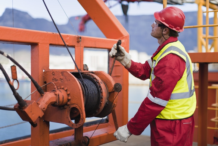 Worker spooling cord on oil rig