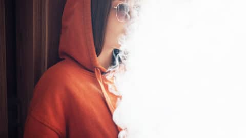 girl smokes vaporizer exhaling a lot of steam