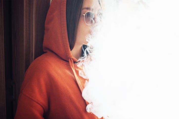 girl exhaling a cloud of smoke