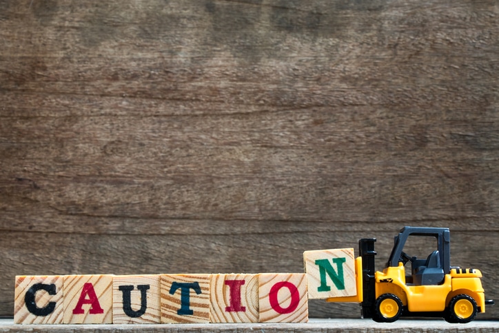 Toy forklift spelling the word Caution with wood blocks