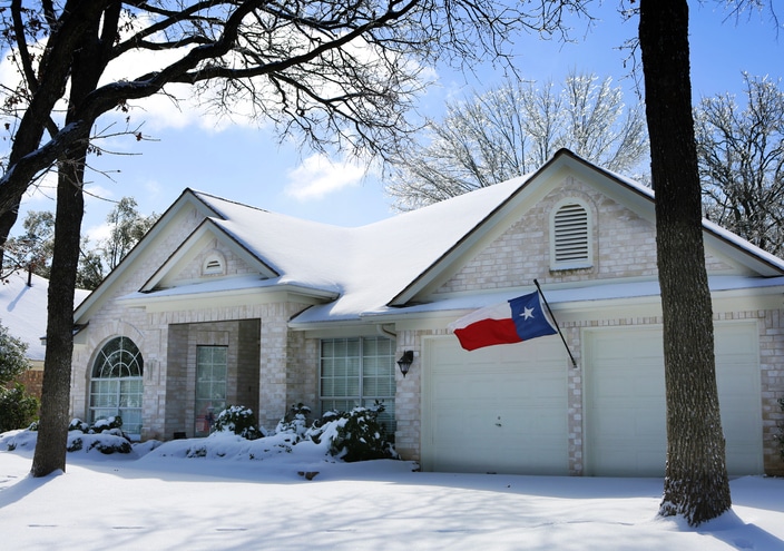 house with snow and Texas flag