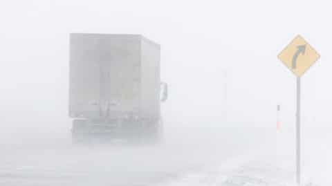 Semi truck driving in snow storm image