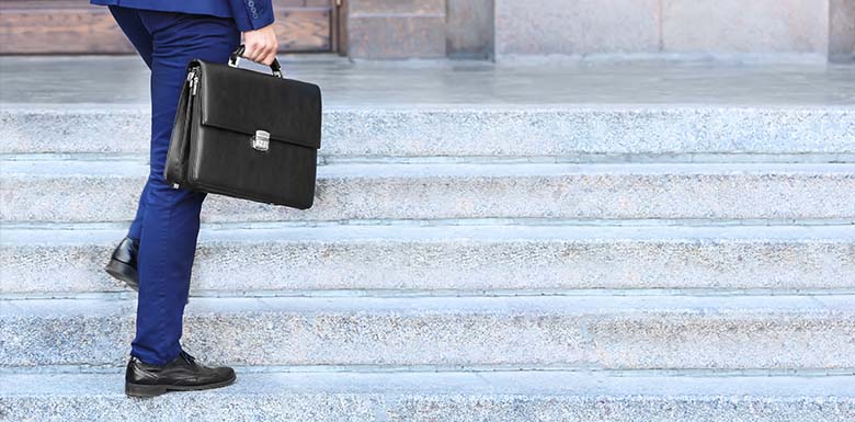 Man in suit with briefcase walking up marble stairs
