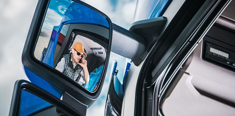Semi truck driver in the reflection of his mirror