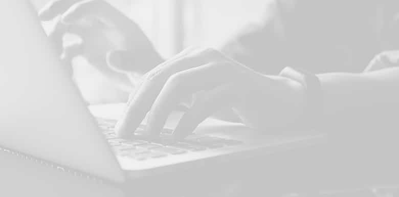 Hands typing on a laptop keyboard, with a focus on the fingers and the keys.